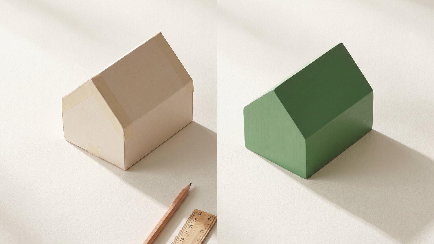 A simple house shape modelled in pale card standing beside the same shape finished in green wood